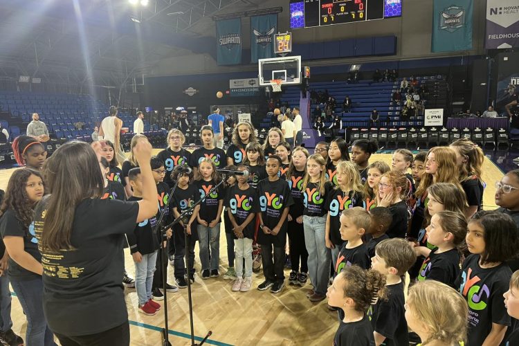 Greensboro Youth Chorus sings the National Anthem at a Swarm game as the players warm up behind them.