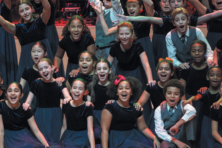 Young Peoples Chorus of New York City, smiling, laughing, and posing on stage