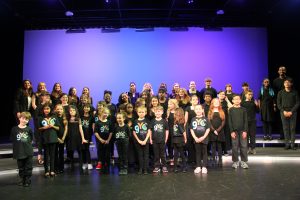 Greensboro Youth Chorus smiles on stage as parents take pics after their spring concert