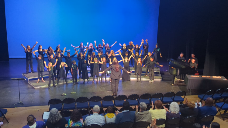 Greensboro Youth Chorus performs at the Van Dyke Performance Space while raising their arms in choreography