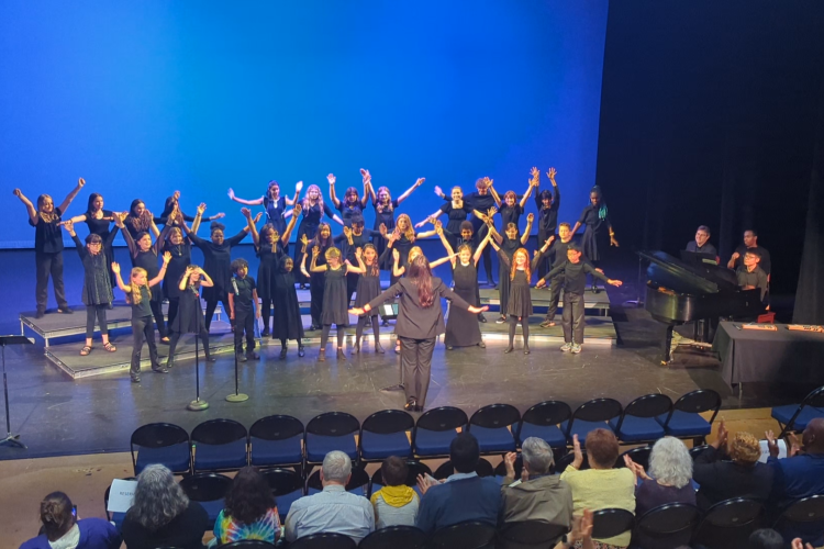 Greensboro Youth Chorus performs at the Van Dyke Performance Space while raising their arms in choreography