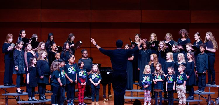 LJ Martin conducts Greensboro Youth Chorus Music Explorers, Apprentice Choir, and Concert choir on stage at Tew Recital Hall